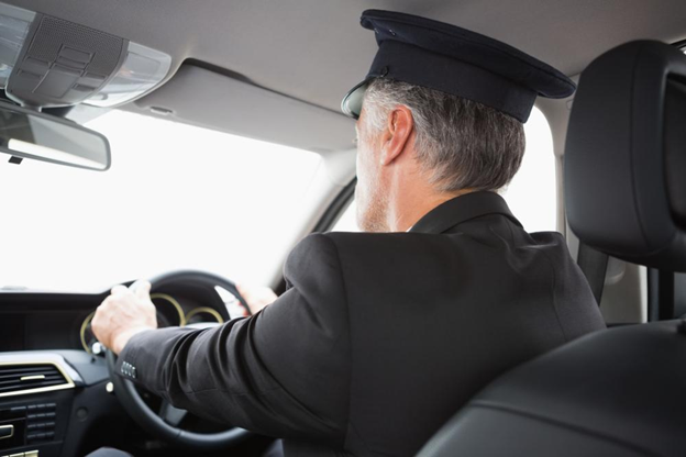 A suited chauffeur at the steering of a vehicle